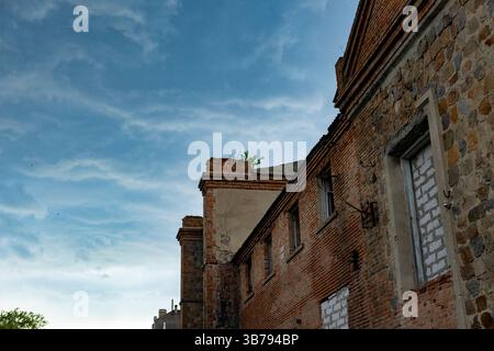 An old brick building stands tall against a backdrop of dark storm clouds. The dramatic sky and ancient architecture create a mysterious, ominous atmo Stock Photo
