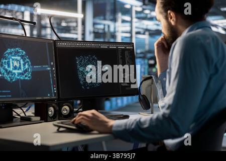 Software developer using computer to oversee server cabinets doing data intensive operations. IT specialist using PC to supervise supercomputers maintaining storage for machine learning Stock Photo