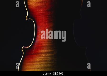 Detail of old violin music instrument of orchestra closeup isolated on black. Silhouette of a violin on black background with copy space for music con Stock Photo
