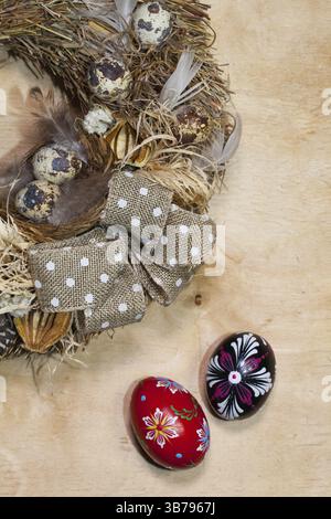 Easter wreath with dry grass, pine cones, feathers, quail and Easter eggs on the wooden table Stock Photo