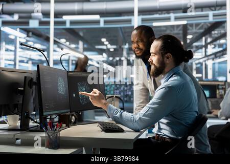 Team of programmers using computer in data center, integrating AI driven automation tools. Server farm IT experts working together, using artificial intelligence machine learning models Stock Photo