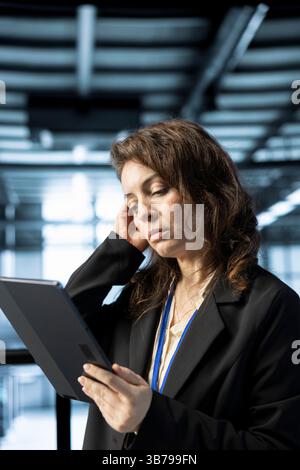 Computer scientist in data center with tablet integrating automation tools, running predictive maintenance routines. Woman ensuring continuous uptime of server room, managing data flows with device Stock Photo