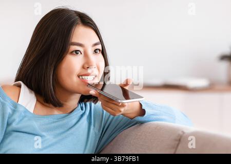 Young woman using voice assistant on smartphone Stock Photo