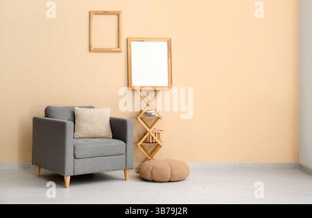 Armchair with pouf, shelves and photo frames on beige wall Stock Photo