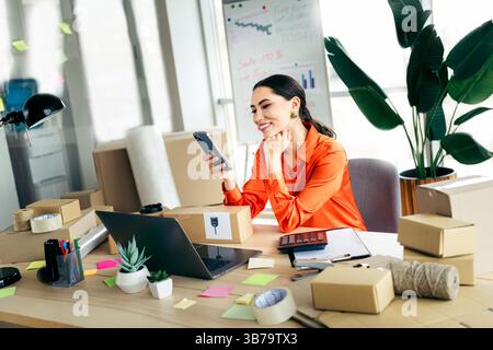 Young female entrepreneur managing ecommerce orders in a stylish workspace Stock Photo