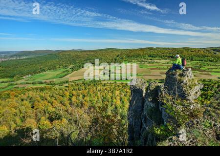 Man hiking sitting on twin rocks above the valley, Waberla, Kirchehrenbach, Franconian Switzerland, Franconia, Bavaria, Germany Stock Photo