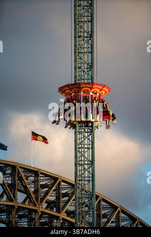 Visitors enjoy the Hair Raiser Ride at Sydney Luna Park with the Sydney Harbour Bridge in the background. Stock Photo