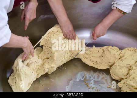 Kneading dough with skilled hands in a bustling bakery during the early morning hours Stock Photo