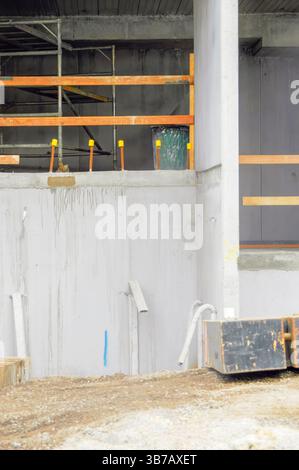 Work-in-progress on a construction site with visible scaffolding, concrete walls, and assorted tools and materials Stock Photo