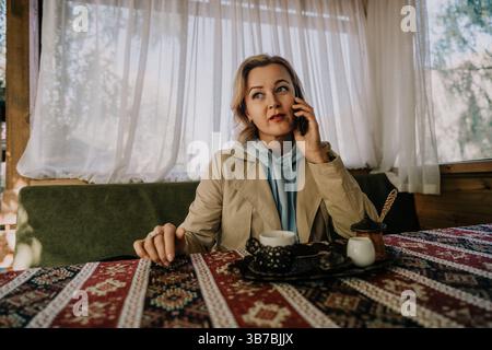 Woman on a Phone Call in a Cozy Cafe Setting Stock Photo