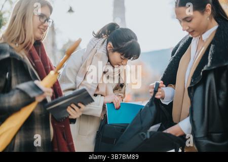 Three Women Collaborating Outdoors on a Sunny Day in Casual Attire Stock Photo