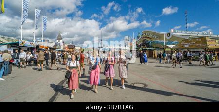 visitors, many in traditional costums stream into Munich Oktoberfest fairground along the Wirtsbudenstraße main thoroughfare, Bavaria, Germany Stock Photo