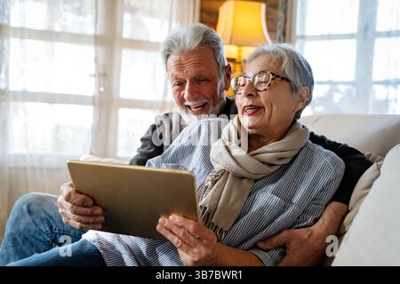 Elderly couple enjoying a tablet. Senior man and woman smiling, bonding over technology. Stock Photo
