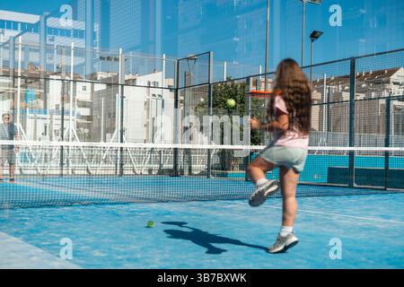 Young woman playing padel tennis on sunny day, action shot. Stock Photo