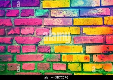 Colorful brick wall made of handmade clay bricks. Abstract bricks background. Bright pink green gradient colored Stock Photo