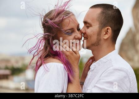 Two people share a joyful moment, smiling and embracing each other warmly. woman has colorful hair, and they enjoy a breezy day outdoor, surrounded by Stock Photo
