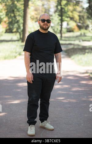 Vertical photo of a man in the park. Black clothes and sunglasses. Stock Photo