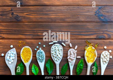 Assortment of Pills and Supplements on Wooden Spoons. A variety of pills, capsules, and supplements are neatly displayed on wooden spoons laid. Top Stock Photo