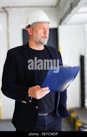 Professional engineer or foreman evaluating progress at work site, indoor setting. Stock Photo
