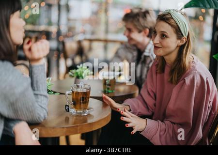 Group of friends chatting over tea in a cozy cafe setting Stock Photo