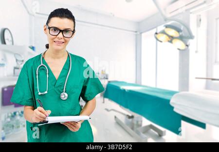 Female doctor with stethoscope in operating room holding clipboard with operating room in background. concept of healthcare and medicine treatment of Stock Photo