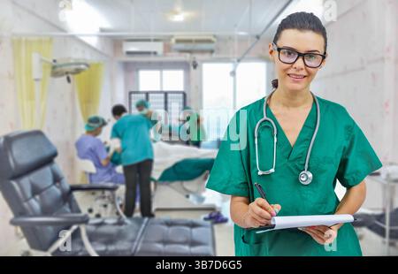 Female doctor with stethoscope in operating room holding clipboard with operating room in background. concept of healthcare and medicine treatment of Stock Photo