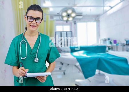 Female doctor with stethoscope in operating room holding clipboard with operating room in background. concept of healthcare and medicine treatment of Stock Photo