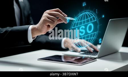 Businessman with laptop touching an icon of a globe with ISO text on tablet screen. Technology innovation on a virtual screen. Concept of ISO certific Stock Photo