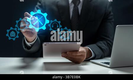Businessman with tablet touching the icon of wrench and screwdriver tools. Technology innovation on a virtual screen. Concept of technical support or Stock Photo