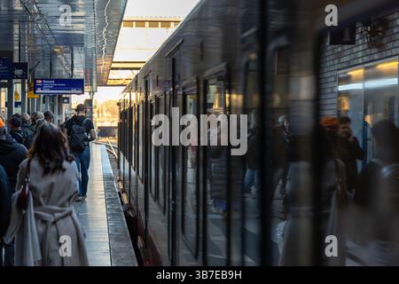 Passengers boarding an S-Bahn train at a busy Berlin station during rush hour. Reflections on the train windows capture the vibrant city commute. Berl Stock Photo