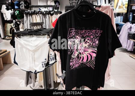 Ivano-Frankivsk, Ukraine - April 29, 2025: Black shirt with vibrant design displayed on rack in retail clothing shop interior Stock Photo