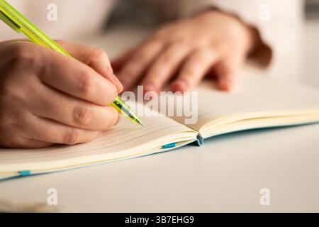 Close up image of human holding pen and writing something on blank white page in notebook Stock Photo