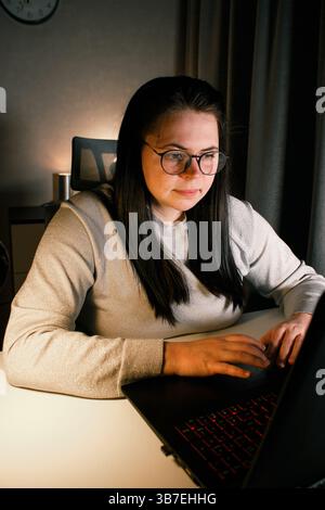 Young freelance accountant working remotely on laptop at home. Managing finances of business. Calculating incomes and expenses. Focusing on process Stock Photo