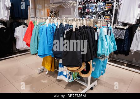 Ivano-Frankivsk, Ukraine - April 29, 2025: Colorful shorts and hats hanging on racks in a modern clothing store. Stock Photo