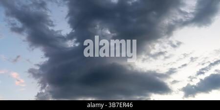 Low angle view of dark sky with strange shape of fluffy black clouds in the morning or evening while sunset or sunrise is used as natural background Stock Photo
