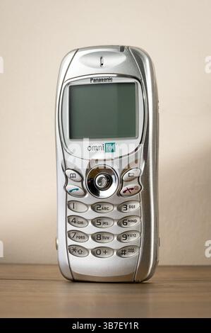 Old silver vintage Panasonic GD75 mobile phone standing on a wooden table, representing past communication technology Stock Photo