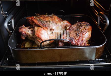 Roasting a whole leg and half leg of lamb in a fan oven with potatoes : Stock Photo