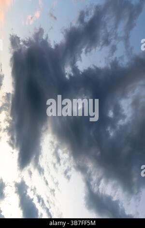 Low angle view of dark sky with strange shape of fluffy black clouds in the morning or evening while sunset or sunrise is used as natural background t Stock Photo
