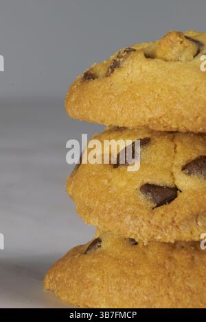 Three stacked chocolate chip cookies, on a gray background with space for text Stock Photo