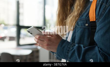 Closeup of male student hands typing on smartphone in university hallway unrecognizable man guy texting message mobile phone browsing online content Stock Photo