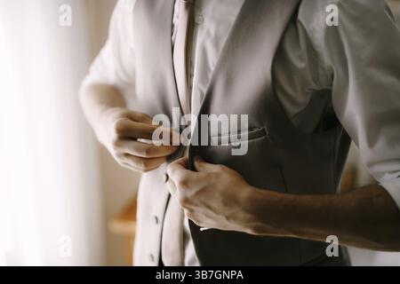 Man in a shirt and tie buttoning the buttons on his vest. Close-up. Stock Photo