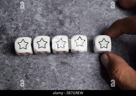 male hand placing wooden cubes or dice with five star on the table. Customer experience or satisfaction survey concept Stock Photo