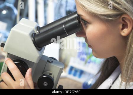 Beauty researcher looking through microscope in laboratory Stock Photo