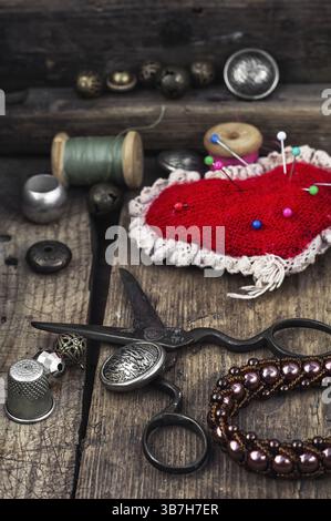Scissors, thread, buttons and needles on wooden vintage background Stock Photo