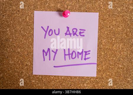 Purple sticky note on cork board saying you are my home Stock Photo