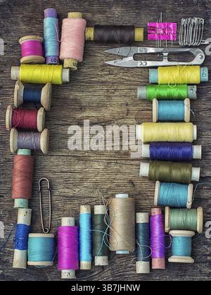 Scissors and thread on old wooden background.Photo tinted Stock Photo