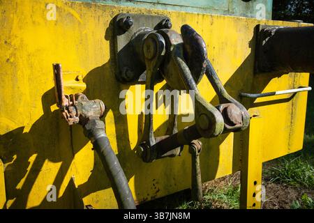 A yellow train car with a rusty bolt on the side. The bolt is missing and the train car is old Stock Photo