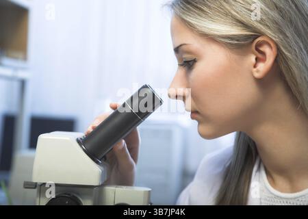 Beauty researcher looking through microscope in laboratory Stock Photo
