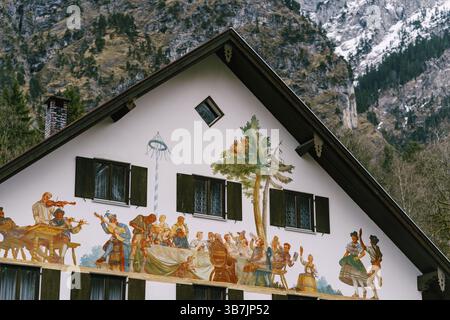 Painted facade of a house in the background of mountains in the village of Oberammergau, Germany. Stock Photo