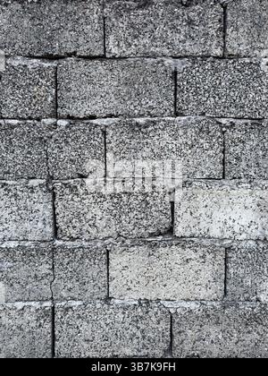 Close-up of rough textured cinder blocks forming an aged concrete wall. Natural lighting, construction detail, no people. Stock Photo